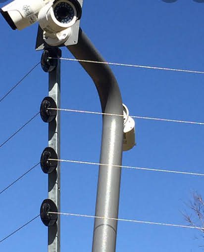 Close-up of an AerixSys electric perimeter fence integrated with a mounted CCTV camera